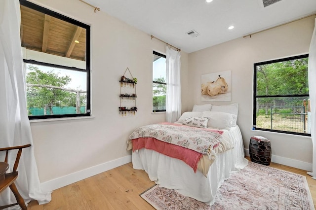 bedroom featuring baseboards, multiple windows, and wood finished floors