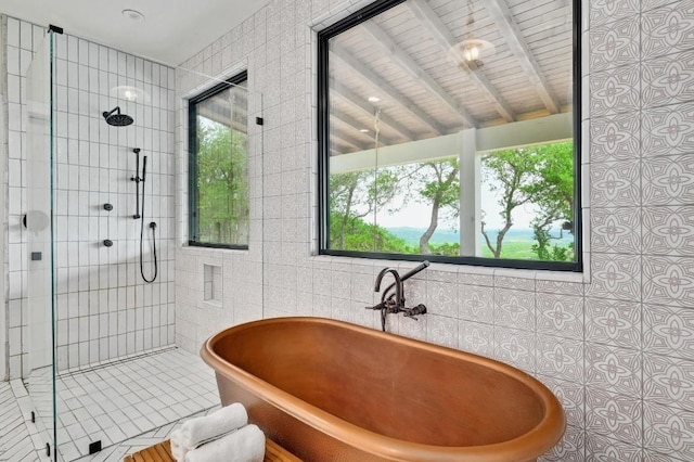bathroom with tile patterned floors, tile walls, a freestanding bath, and a shower stall