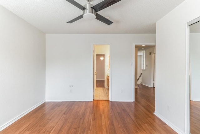 14400 Weldon Ln, Austin, TX 78728 - unfurnished bedroom with wood finished floors, baseboards, ceiling fan, and a textured ceiling