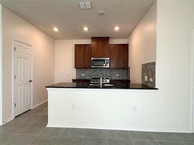 4482 Acerno St, Round Rock, TX 78665 - kitchen featuring stainless steel microwave, dark countertops, backsplash, a peninsula, and recessed lighting