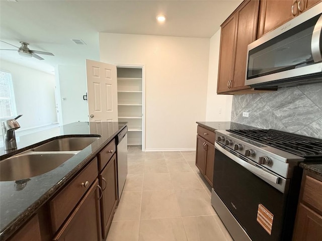 4482 Acerno St, Round Rock, TX 78665 - kitchen with appliances with stainless steel finishes, decorative backsplash, dark stone counters, a ceiling fan, and light tile patterned floors