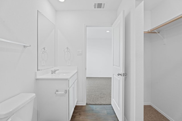 127 Safflower Dr, Uhland, TX 78640 - bathroom featuring toilet, baseboards, visible vents, vanity, and wood finished floors