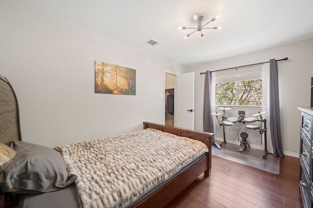 905 Whispering Hollow Dr, Kyle, TX 78640 - bedroom with an inviting chandelier, a textured ceiling, visible vents, and dark wood-type flooring