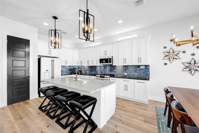 kitchen with white appliances, visible vents, a sink, and light wood-style floors
