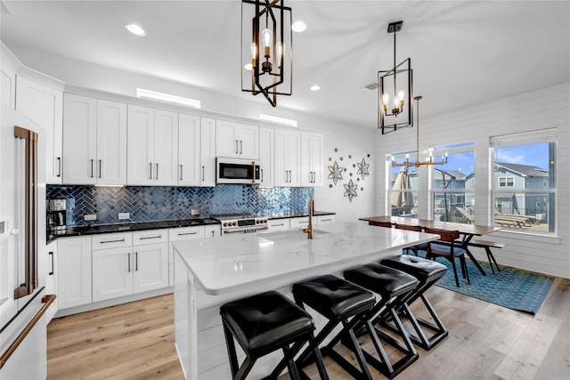 kitchen featuring gas range oven, a notable chandelier, white microwave, and light wood-style flooring