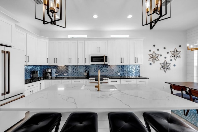 kitchen featuring a notable chandelier, decorative backsplash, a sink, and white microwave