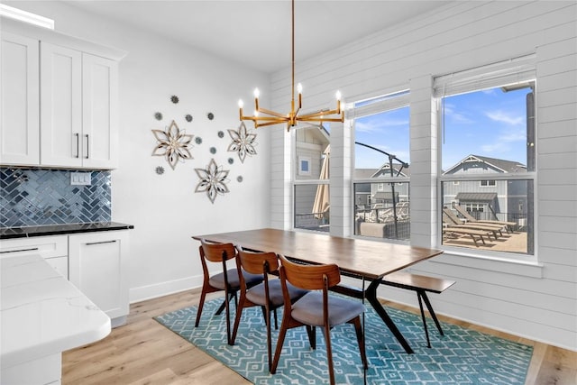 dining area featuring plenty of natural light, light wood-style flooring, a chandelier, and wooden walls