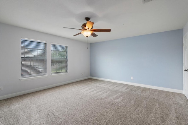 carpeted spare room featuring baseboards and ceiling fan