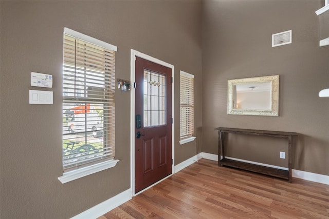 entrance foyer with visible vents, wood finished floors, and baseboards