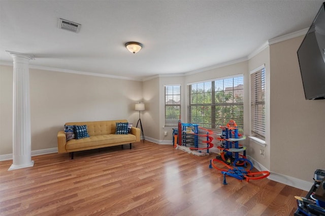 rec room with wood finished floors, decorative columns, visible vents, baseboards, and ornamental molding