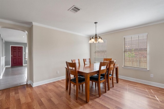 dining area featuring ornamental molding, baseboards, visible vents, arched walkways, and a notable chandelier