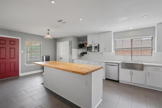 kitchen with butcher block counters, visible vents, a sink, backsplash, and appliances with stainless steel finishes