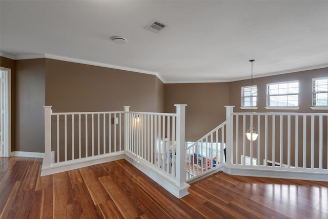 corridor with ornamental molding, visible vents, and wood finished floors