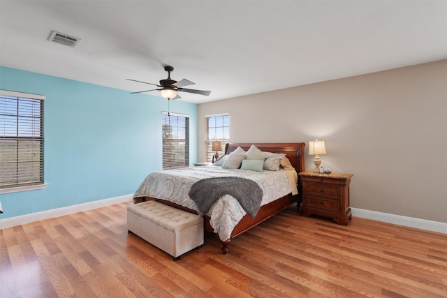 bedroom featuring baseboards, multiple windows, and light wood-style flooring