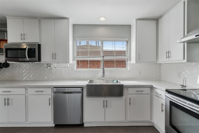 kitchen featuring white cabinetry, light countertops, appliances with stainless steel finishes, and wall chimney exhaust hood