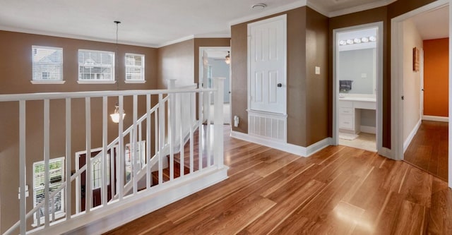 hallway featuring wood finished floors, an upstairs landing, visible vents, crown molding, and baseboards