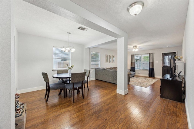 dining area with a textured ceiling, baseboards, dark wood-style flooring, visible vents, and ceiling fan with notable chandelier