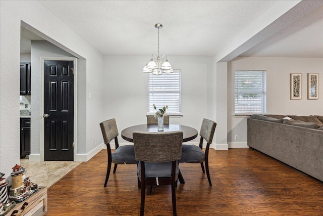 dining room with baseboards, a notable chandelier, and wood finished floors