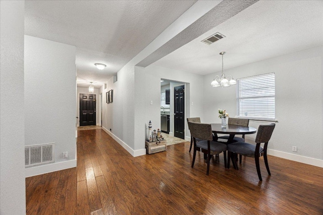 dining room with baseboards, dark wood finished floors, visible vents, and a textured ceiling