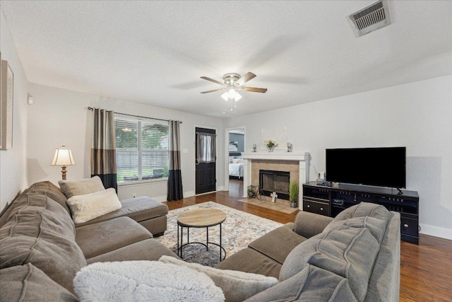living room with wood finished floors, visible vents, ceiling fan, baseboards, and a tile fireplace
