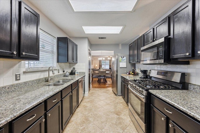 kitchen featuring light stone countertops, visible vents, a sink, tasteful backsplash, and appliances with stainless steel finishes