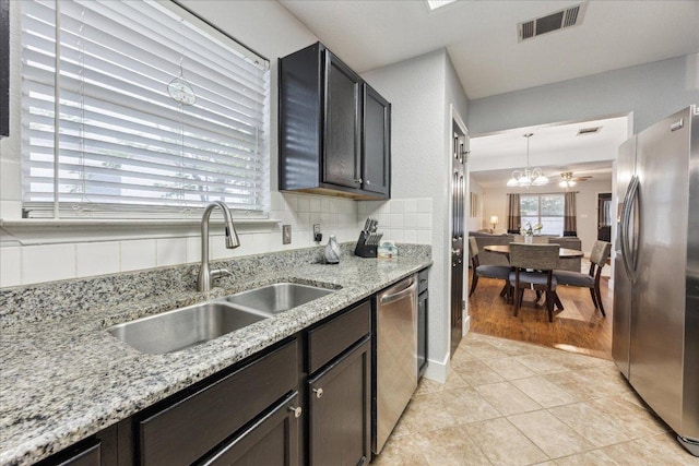 kitchen featuring a sink, a notable chandelier, visible vents, light stone countertops, and appliances with stainless steel finishes