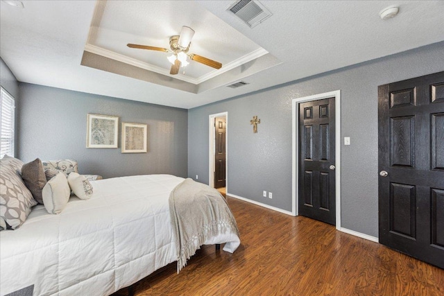 bedroom featuring crown molding, visible vents, wood finished floors, and a raised ceiling