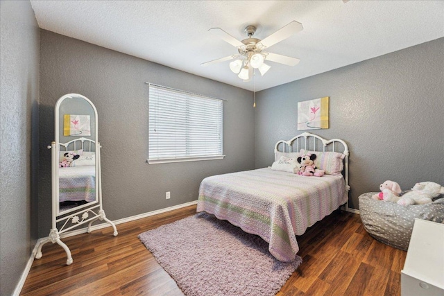 bedroom featuring a ceiling fan, wood finished floors, baseboards, and a textured wall