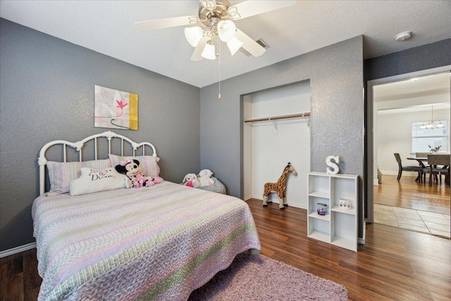 bedroom featuring wood finished floors, a closet, visible vents, ceiling fan, and a textured wall
