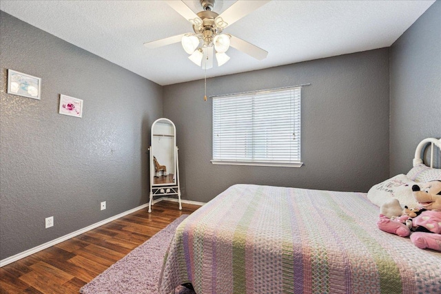 bedroom with ceiling fan, a textured wall, baseboards, and wood finished floors