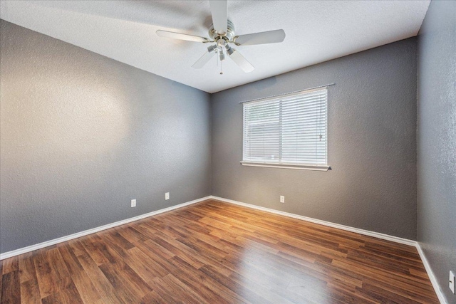 empty room featuring ceiling fan, a textured wall, baseboards, and wood finished floors