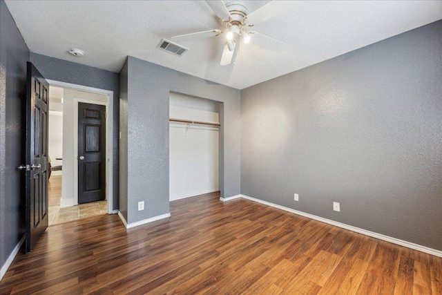 unfurnished bedroom with visible vents, wood finished floors, baseboards, and a textured wall