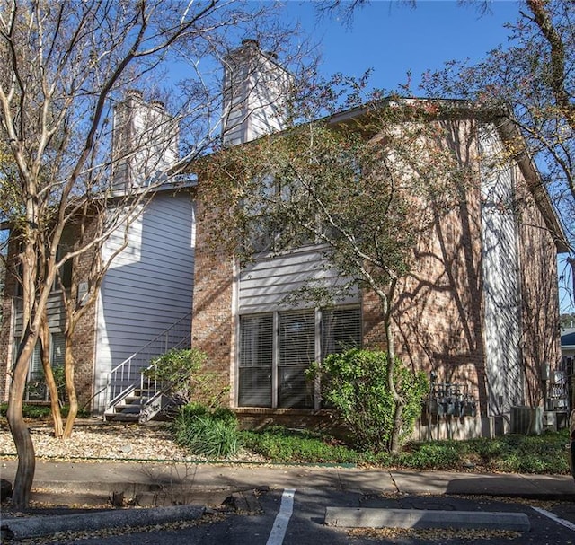 view of home's exterior with brick siding, stairway, and a chimney