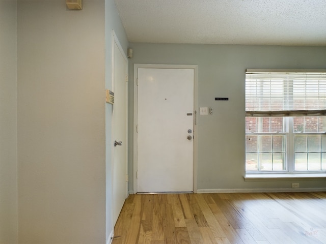 entryway featuring light wood-type flooring, baseboards, and a textured ceiling