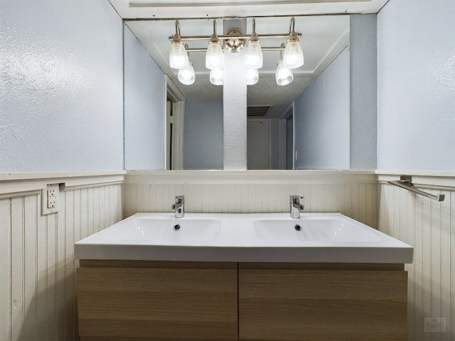 bathroom featuring double vanity, a wainscoted wall, and a sink