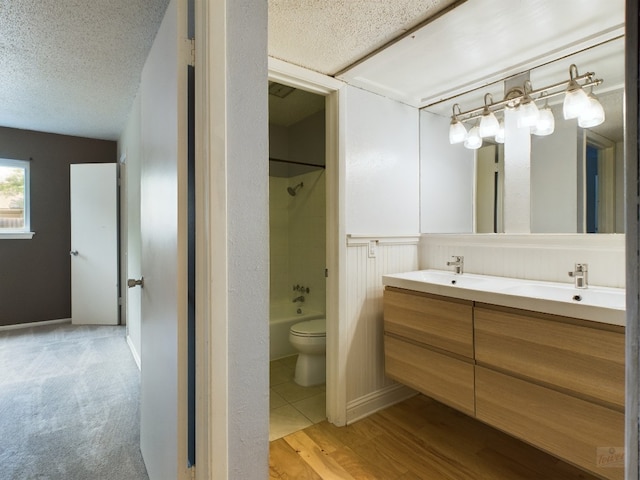 7920 Rockwood Ln Unit 115, Austin, TX 78757 - bathroom with double vanity, bathtub / shower combination, a textured ceiling, and wood finished floors
