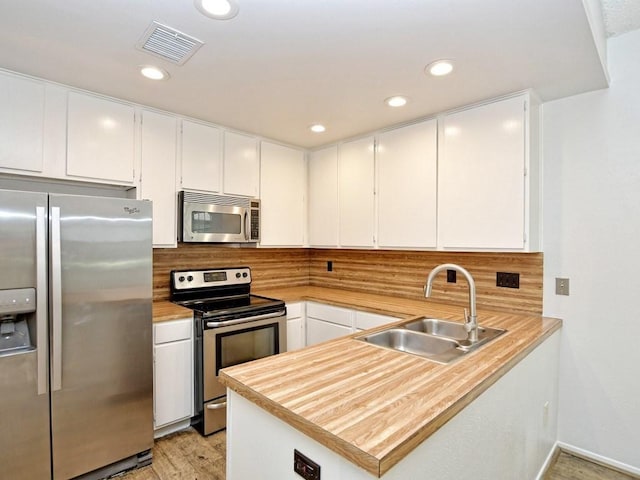 kitchen with a sink, tasteful backsplash, visible vents, white cabinetry, and appliances with stainless steel finishes
