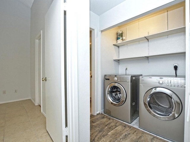 clothes washing area with washing machine and clothes dryer, baseboards, and laundry area
