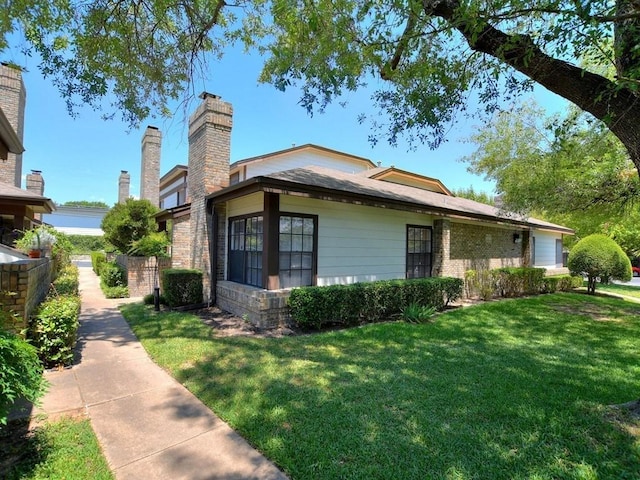 view of side of home with a yard and a chimney