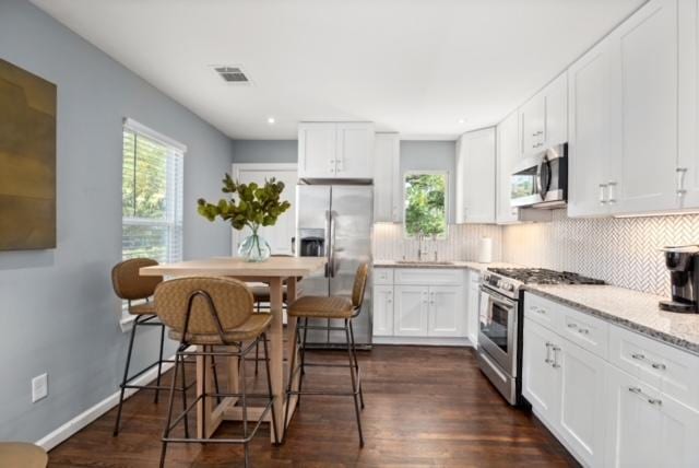 1183 Coleto St, Austin, TX 78702 - kitchen with stainless steel appliances, tasteful backsplash, white cabinets, dark wood finished floors, and recessed lighting