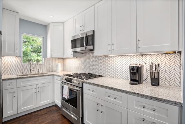1183 Coleto St, Austin, TX 78702 - kitchen with appliances with stainless steel finishes, a sink, white cabinetry, light stone counters, and backsplash