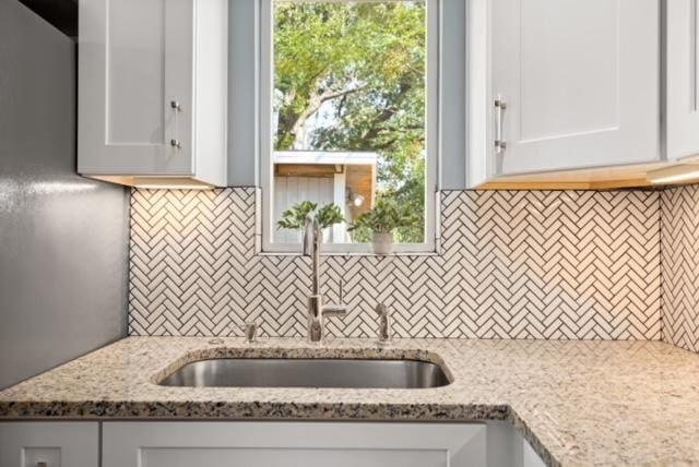 1183 Coleto St, Austin, TX 78702 - kitchen with a sink, backsplash, light stone countertops, and white cabinetry