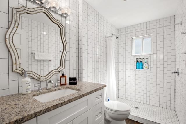 1183 Coleto St, Austin, TX 78702 - bathroom with a stall shower, vanity, toilet, and tile walls