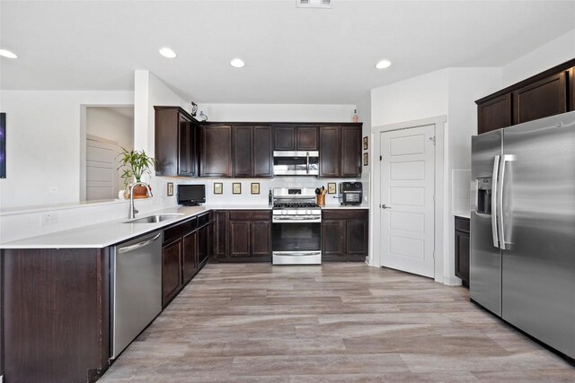 8220 Linnie Ln, Austin, TX 78724 - kitchen featuring stainless steel appliances, dark brown cabinets, a sink, light wood-type flooring, and light countertops
