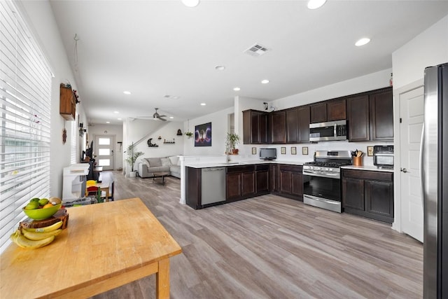 8220 Linnie Ln, Austin, TX 78724 - kitchen with stainless steel appliances, open floor plan, dark brown cabinets, light wood-type flooring, and light countertops