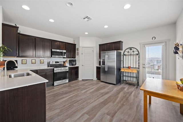 8220 Linnie Ln, Austin, TX 78724 - kitchen with stainless steel appliances, a sink, dark brown cabinetry, light countertops, and light wood-style floors