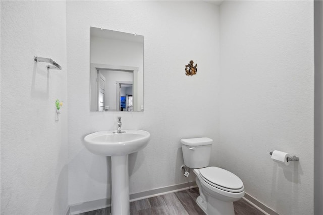 8220 Linnie Ln, Austin, TX 78724 - half bath featuring wood finished floors, toilet, baseboards, and a sink