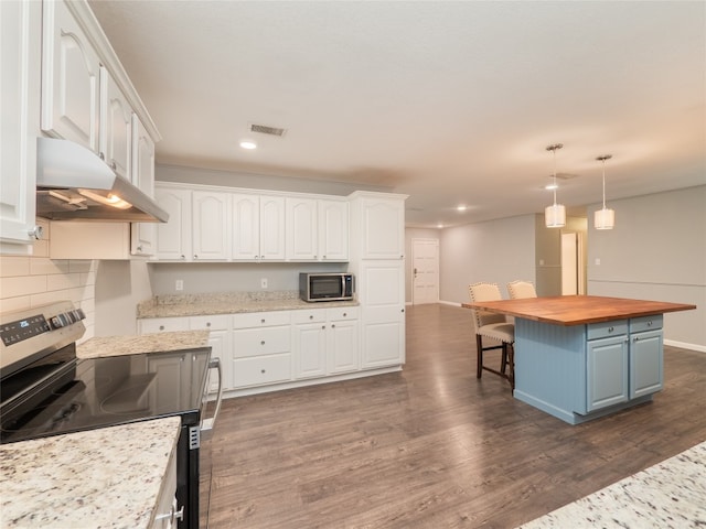 kitchen with appliances with stainless steel finishes, under cabinet range hood, white cabinets, butcher block countertops, and recessed lighting