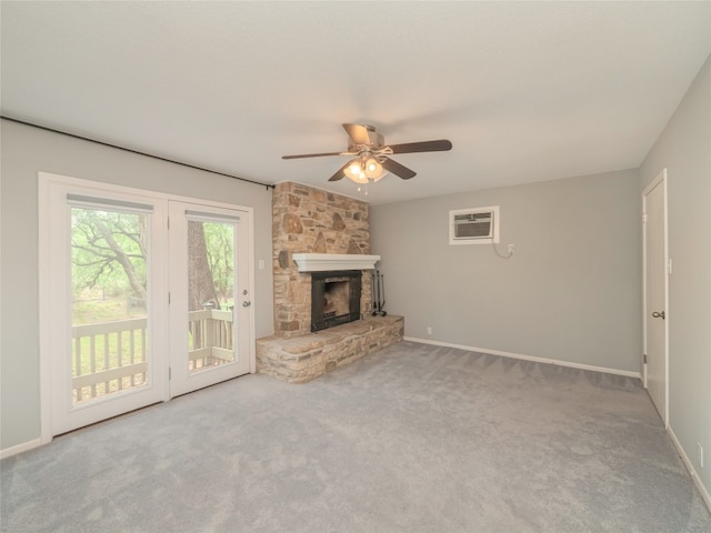 unfurnished living room featuring a ceiling fan, carpet floors, a stone fireplace, and a wall mounted AC