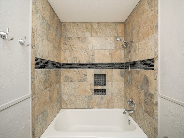 bathroom with a textured wall and shower / bathtub combination